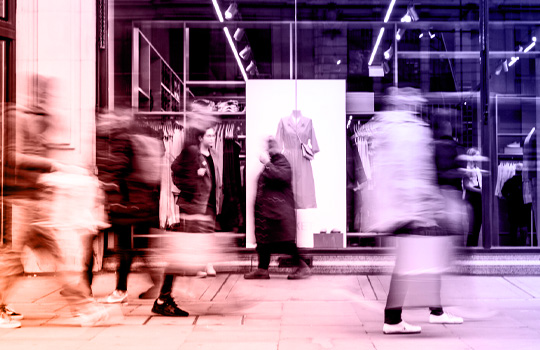 Pedestrians walk by a luxury brand storefront.