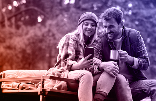 Travelers are enjoying a moment in nature, using a smartphone to plan their next adventure.