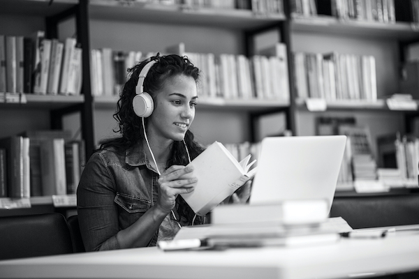 Frau beim online Learning mit Computer und Kopfhörern in Arbeitsumfeld