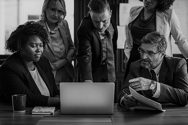 five business people circled around a computer representing Lionbridge Branislav Sulovsky's passion for teamwork