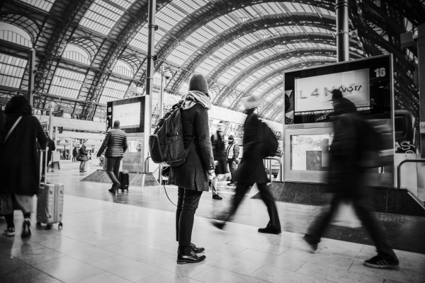 Person looking at tv screen in busy train station - representing a setting to avoid risks of cultural differences in communication