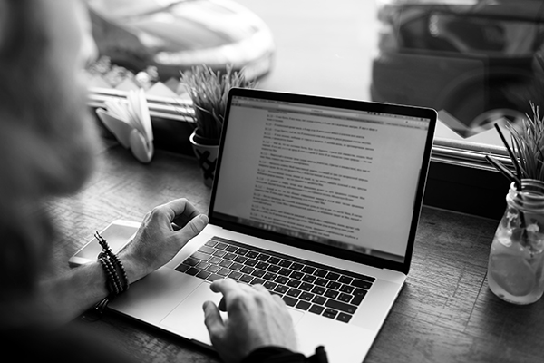 rédacteur de contenus professionnels travaillant sur une page web via un ordinateur portable assis dans un café