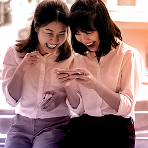 Two people laughing will replying to a message on a mobile phone