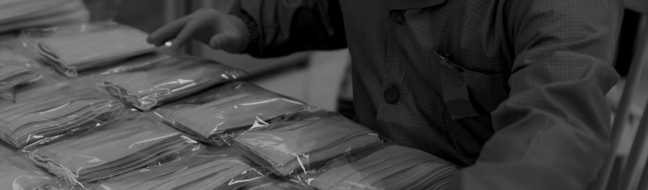 A gloved worker arranges sealed face masks, one of the personal protection equipment types that healthcare workers need to treat COVID-19 patients safely.