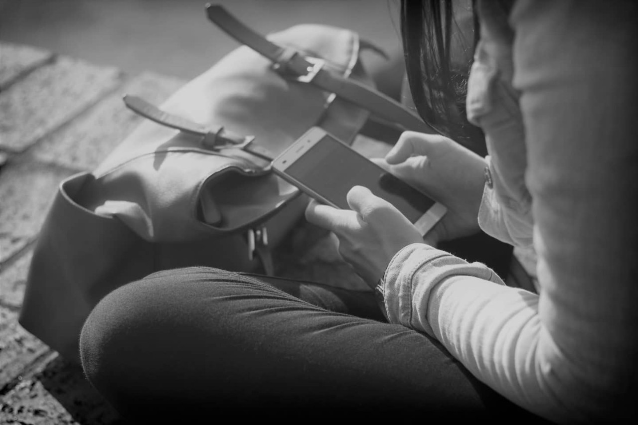 A girl sitting with a mobile phone in her hands