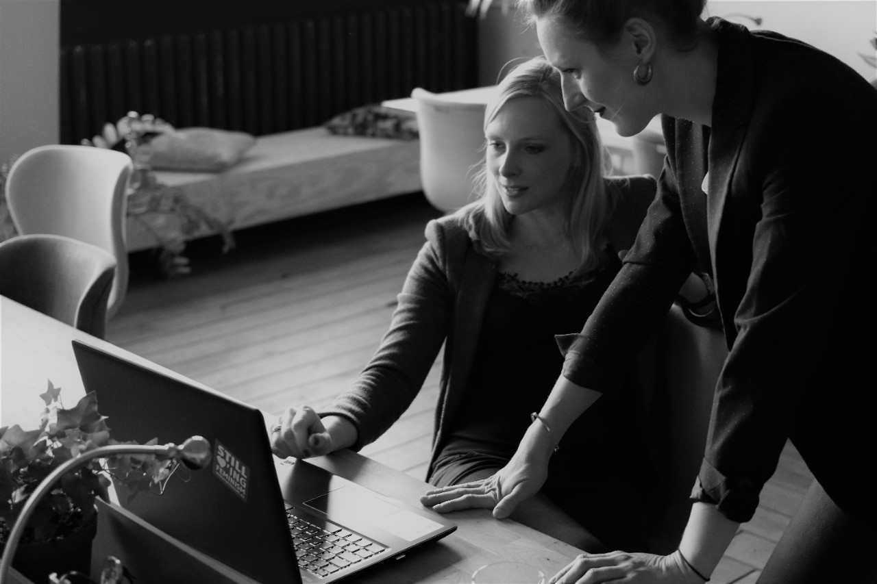 two women communicating before a laptop computer