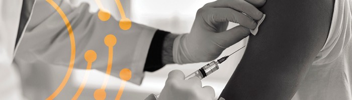 A syringe in a gloved hand next to a bare arm.