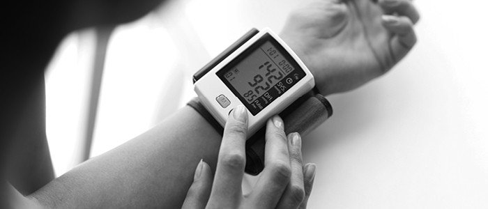 A woman checks her blood pressure using a cuff on her wrist
