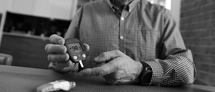 A close-up of a man with a diabetes test strip and one finger extended