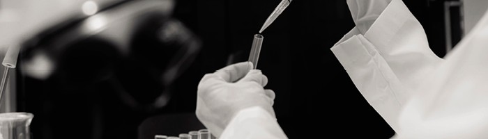 A close-up of someone pipetting a substance into a test tube.