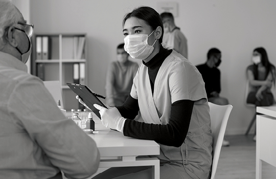 A medical provider speaks with an elderly patient at a vaccine clinic.