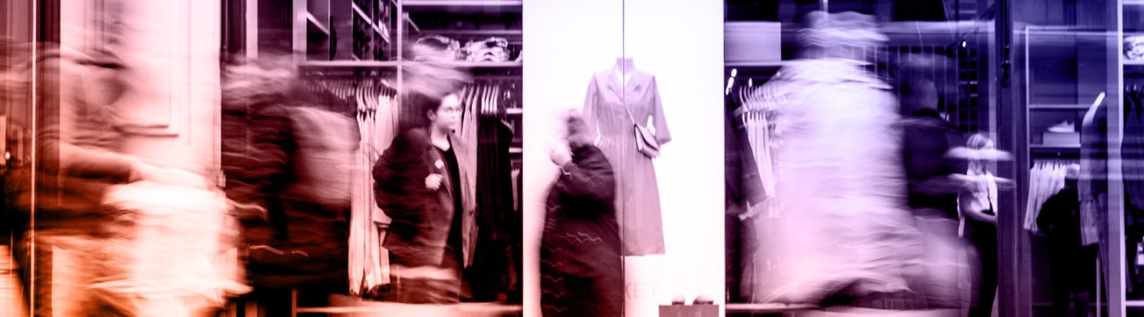 Pedestrians walk by a luxury brand storefront. 