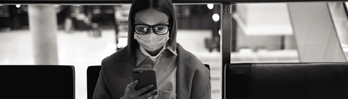 Woman wearing glasses and a face mask looks at her mobile phone