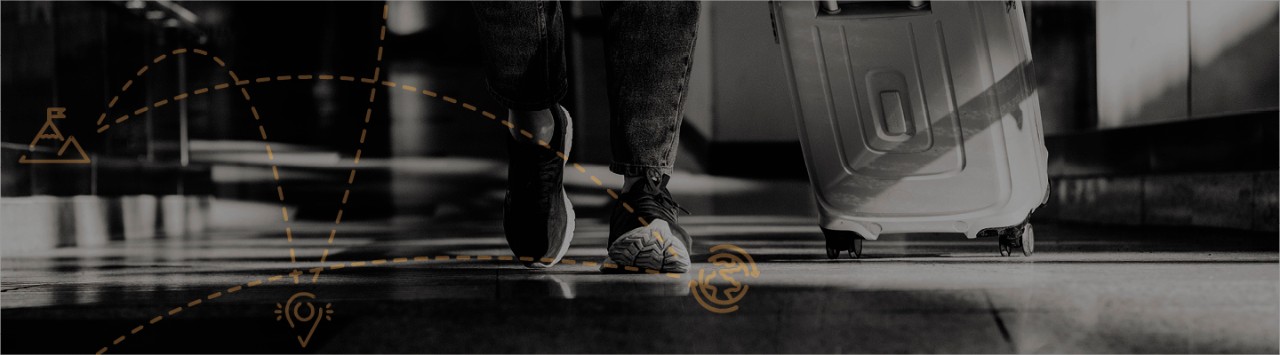 Person shown from the knees down, walking across the floor wearing sneakers and pulling a suitcase  