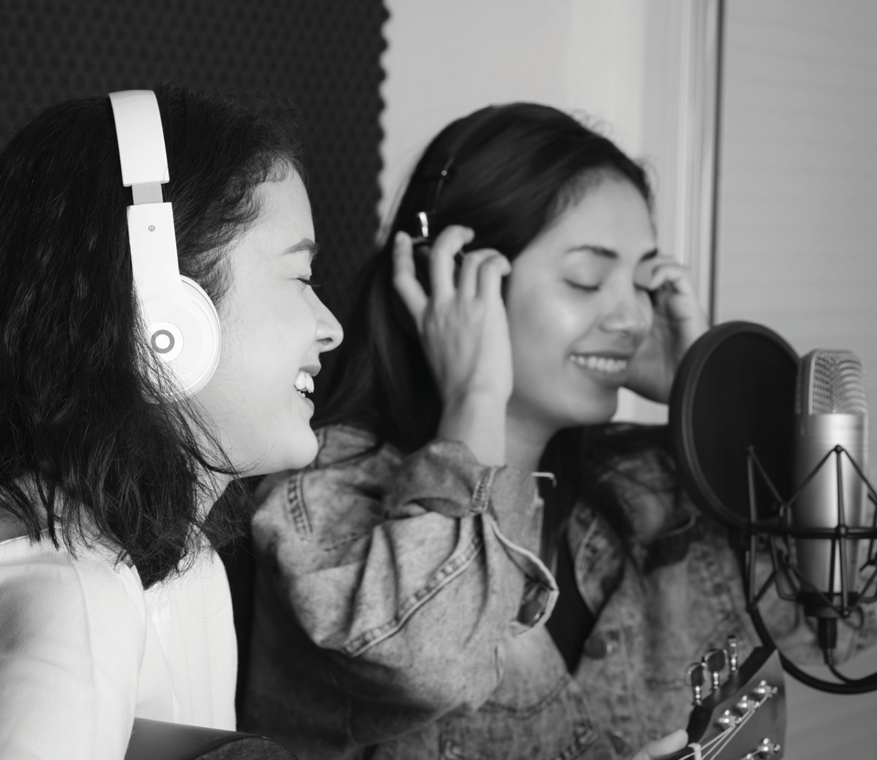 Two people recording sound and laughing in a studio