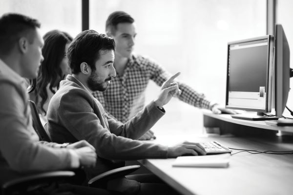 Man working in a group pointing at computer screen