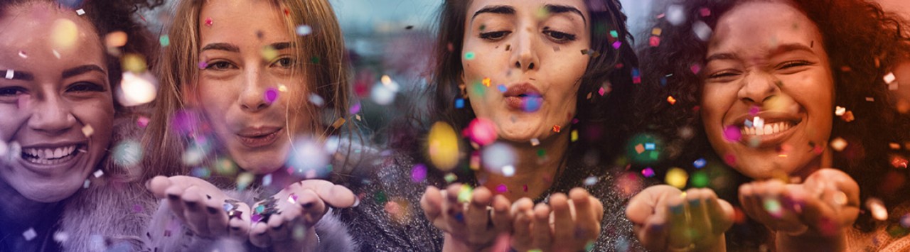 Mujeres multiculturales lanzando purpurina y destellos hacia la cámara 