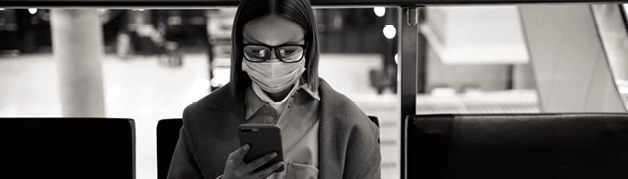 Woman wearing glasses and a face mask looks at her mobile phone