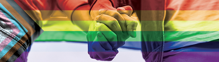 Due persone che si tengono per mano con una bandiera per il mese del Pride