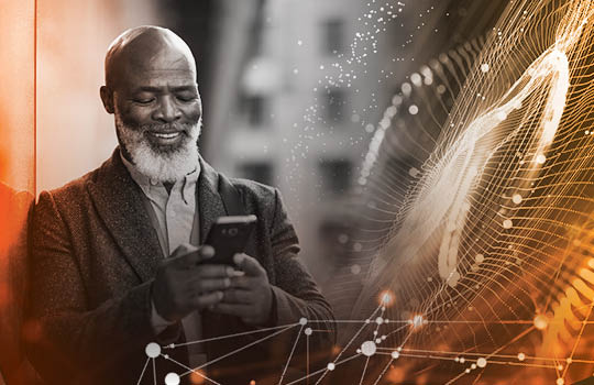 A person in a suit looks at a smartphone next to a technological web superimposed over a building