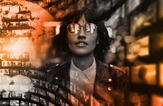 Woman wearing glasses surrounded by monitors