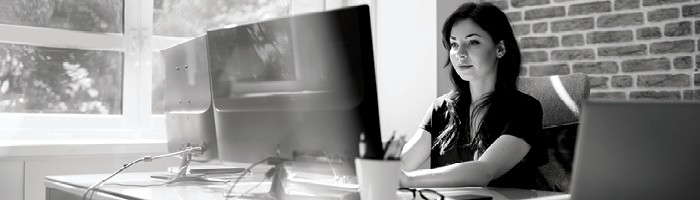Woman sits at desk working at computer.
