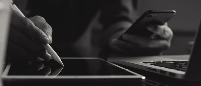 A person writing on a tablet and looking at a phone