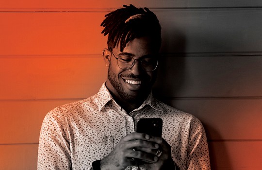 Man smiles as he reads something on his mobile phone.