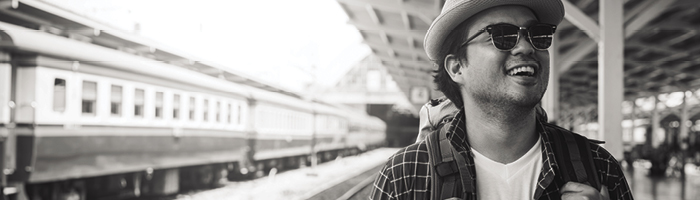 Man at a train station wearing sunglasses smiles