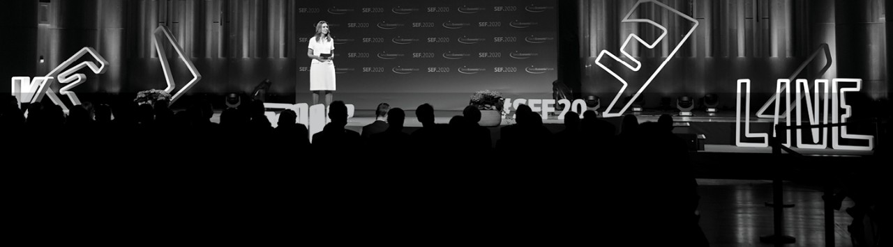 This photo was taken at the 2020 Swiss Economic Forum. A woman stands on stage addressing an audience. The photo represents Lionbridge’s simultaneous interpretation services, which enables speakers to deliver presentations to multilingual audiences.