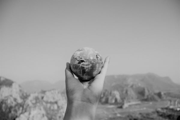 Small globe being held in a hand with skyline of mountains in background
